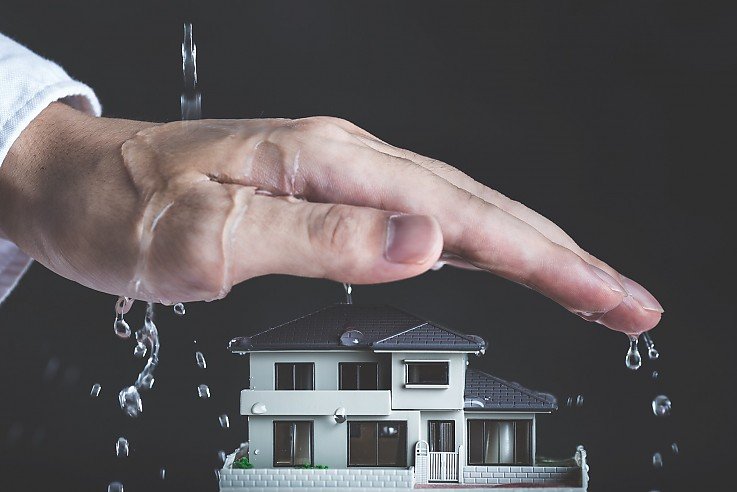 Eine Hand sch�tzt die Immobilie vor Wasser