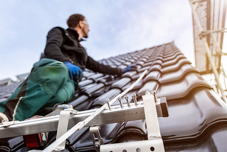 Montage von Solardachziegeln durch Handwerker auf modernem Hausdach � nachhaltige Photovoltaik-Integration.