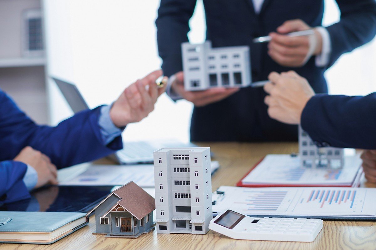 Immobilienprofis besprechen Bauprojekt mit Hausmodellen und Pl�nen am Konferenztisch
