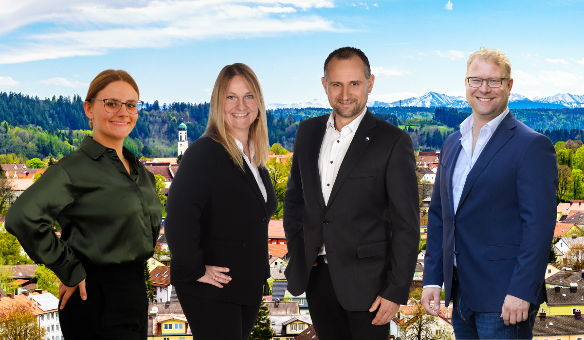 Stockhausen Immobilienteam in Schongau - persönliche und professionelle Beratung beim Immobilienverkauf und -kauf in Schongau Stockhausen Immobilienteam Schongau - vier Immobilienmakler vor dem Stadtpanorama Schongau mit Alpen und Kirchturm im Hintergrund